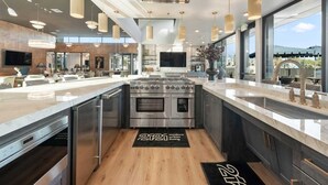 Una cucina moderna con elettrodomestici in acciaio inossidabile, una grande isola centrale e luci a sospensione.