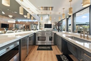 A modern kitchen with stainless steel appliances, a large island, and pendant lighting.