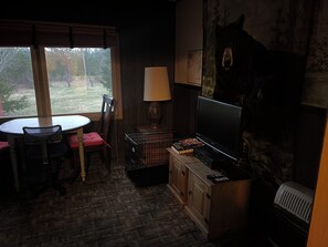 Une pièce comprenant une table, des chaises, un téléviseur, une lampe et un tableau accroché au mur.