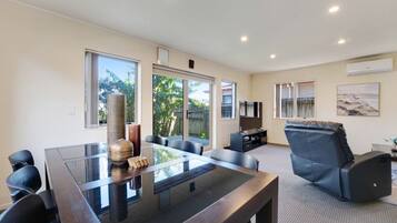 A modern living room with a glass-top table, leather sofa, and a flat-screen TV.