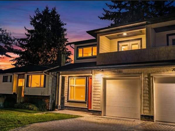 Ein modernes, zweistöckiges Haus mit Garage, Auffahrt und gepflegtem Rasen.