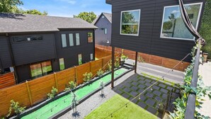 A modern two-story house with a fenced backyard, a small garden area, and a visible staircase leading to the upper floor. - SoCo Serene Austin Way to Go! (Austin)