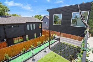 Ein modernes, zweistöckiges Haus mit eingezäuntem Garten, einem kleinen Gartenbereich und einer sichtbaren Treppe, die zum Obergeschoss führt.