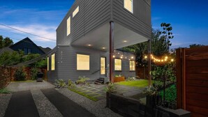 A modern two-story house with a covered porch, a well-maintained lawn, and a gravel driveway. - SoCo Serene Austin Way to Go! (Austin)