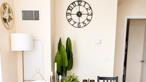 A dining area with a round table, chairs, a clock, a potted plant, and a lamp. - Entire Beautiful Apartment in Downtown Mississauga (Mississauga)