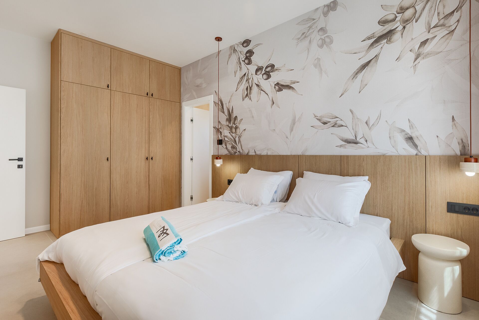 Un dormitorio con cama, armario de madera y una pared con estampado floral.