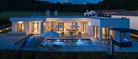 Una casa moderna con piscina, mobiliario exterior y zona de patio.