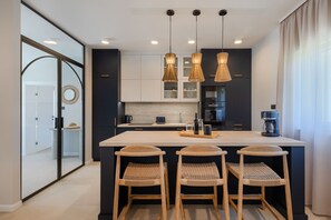 A modern kitchen with a central island, pendant lighting, and a view of the adjacent bathroom. - Villa Dell' Arte (Istria - Žminj) (Žminj)