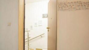 A hotel entrance with a wooden door, a staircase, and a welcome sign. - Minerva Royal Suite - Alghero (Alghero)