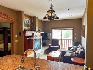 A living room with a fireplace, a television, and a dining area with a table and chairs.