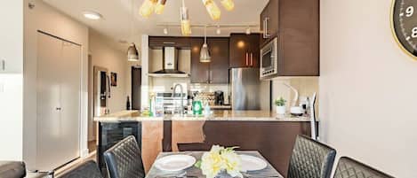 A modern kitchen with dark cabinets, stainless steel appliances, and a central island.