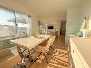 A modern kitchen with a dining area, large windows, and a view of the outdoors.
