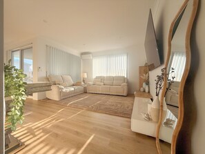 A modern living room with a sofa, a coffee table, a mirror, and a potted plant.