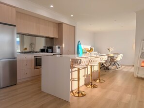 A modern kitchen with wooden cabinets, a central island with bar stools, and a dining area with a table and chairs.