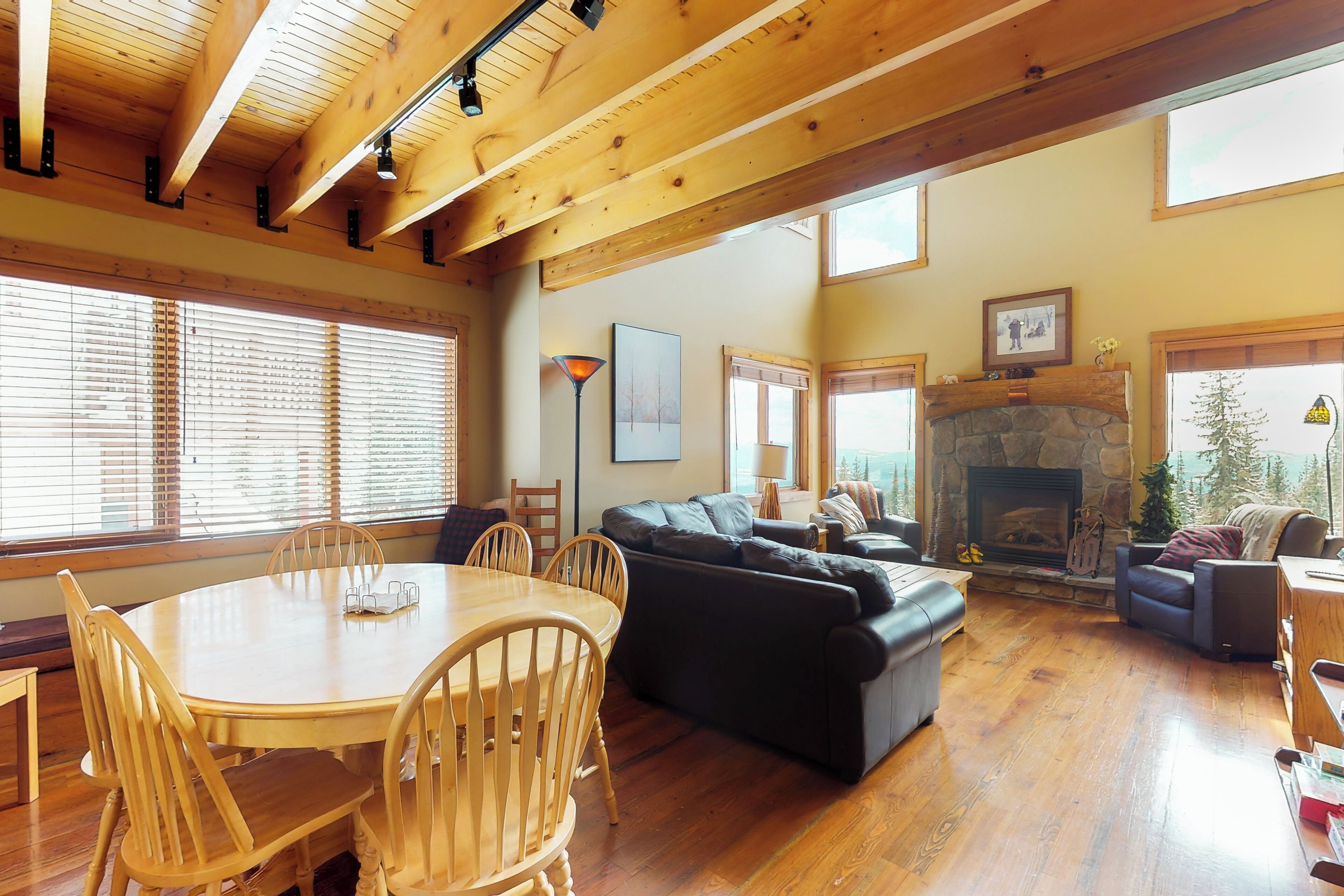 Una sala de estar amplia con chimenea, piso de madera y ventanas grandes.