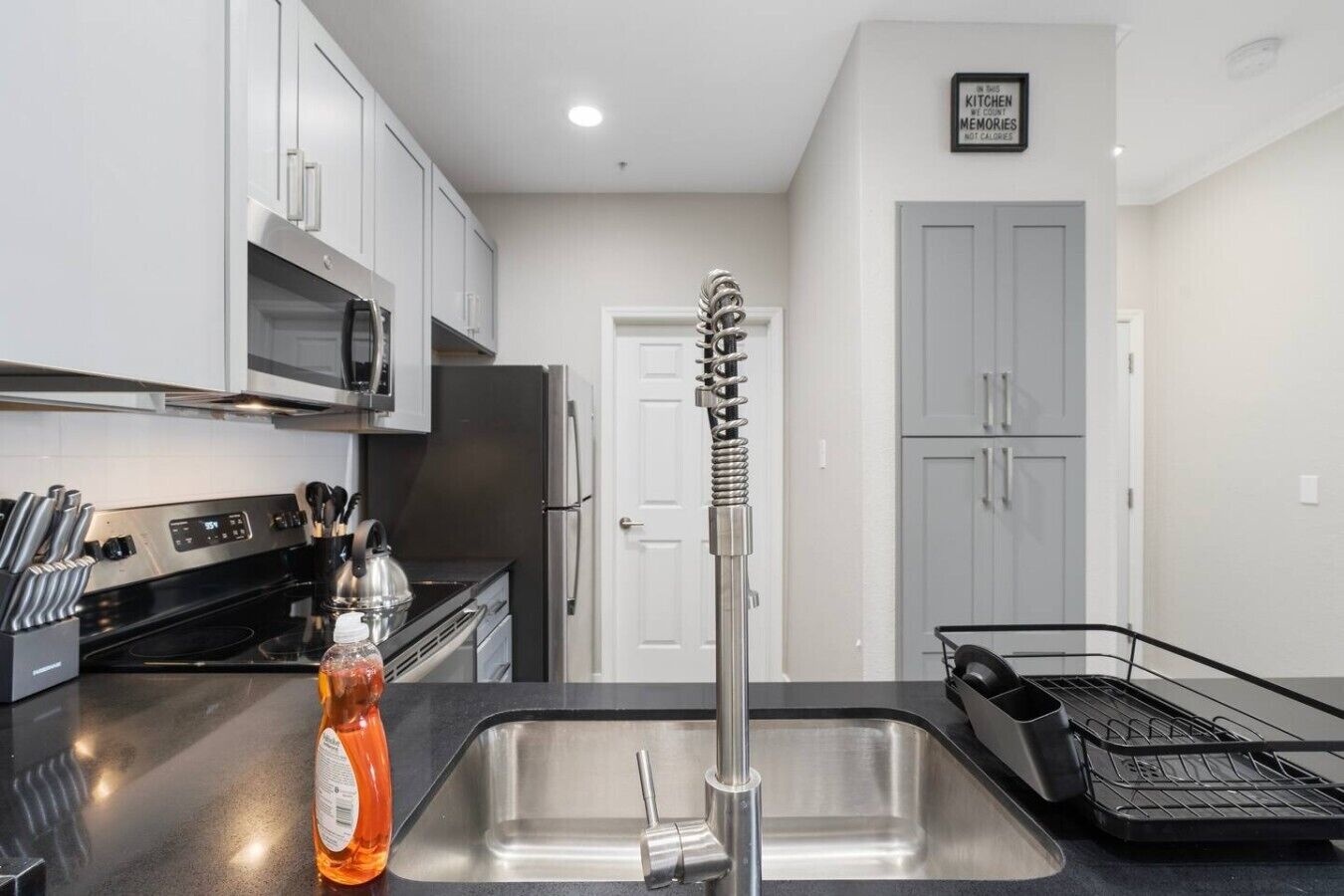 A modern kitchen with stainless steel appliances, a black countertop, and a sink with a faucet.