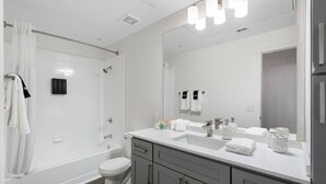 A modern bathroom with a shower, toilet, vanity with a mirror, and a sink. - Your Fun Friendly Stay (Scottsdale)
