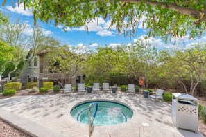 Uma piscina com espreguiçadeiras, rodeada por árvores e um edifício.