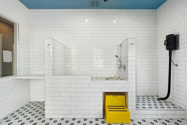 A modern bathroom with white subway tiles, a glass-enclosed shower, a yellow step stool, and a black vacuum hose. - WestWorld, TPC Scottsdale & Mayo Clinic, Pool, Spa (Scottsdale)