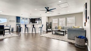 A spacious living area with a sofa, a coffee table, and a dining area with chairs. - Modern Pool House - 15min to the strip! (Las Vegas)