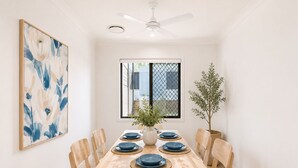 A dining area with a wooden table, blue plates, and chairs. - Murrumba Manor | Elegant Family Escape (Murrumba Downs)