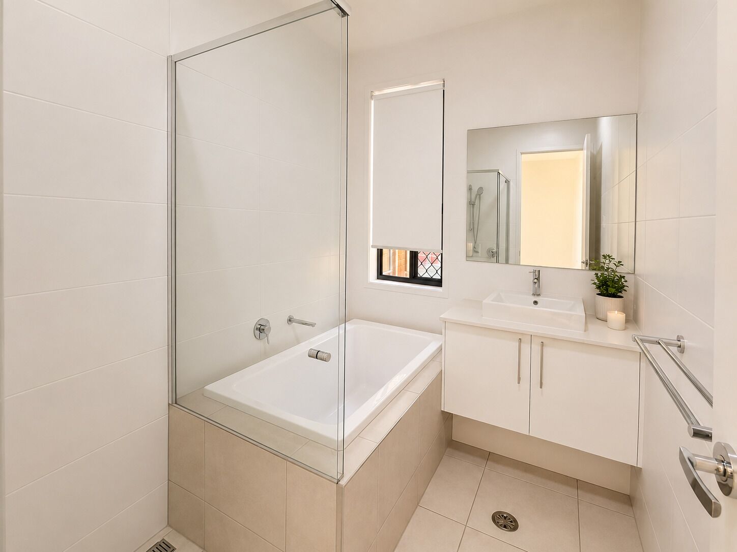 A modern bathroom with a glass-enclosed shower, a white sink with a mirror, and a cabinet.