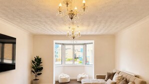 Ein Wohnzimmer mit einer Chandelier, einem Sofa, einem Couchtisch, einer Topfpflanze und einem Fenster mit Blick.