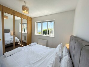 Een slaapkamer met een bed, een raam, een kledingkast en een hanglamp.