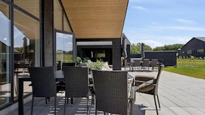Eine moderne Außenpatio mit Korbmöbeln, einer Holzpergola und Blick auf die umliegende Landschaft.