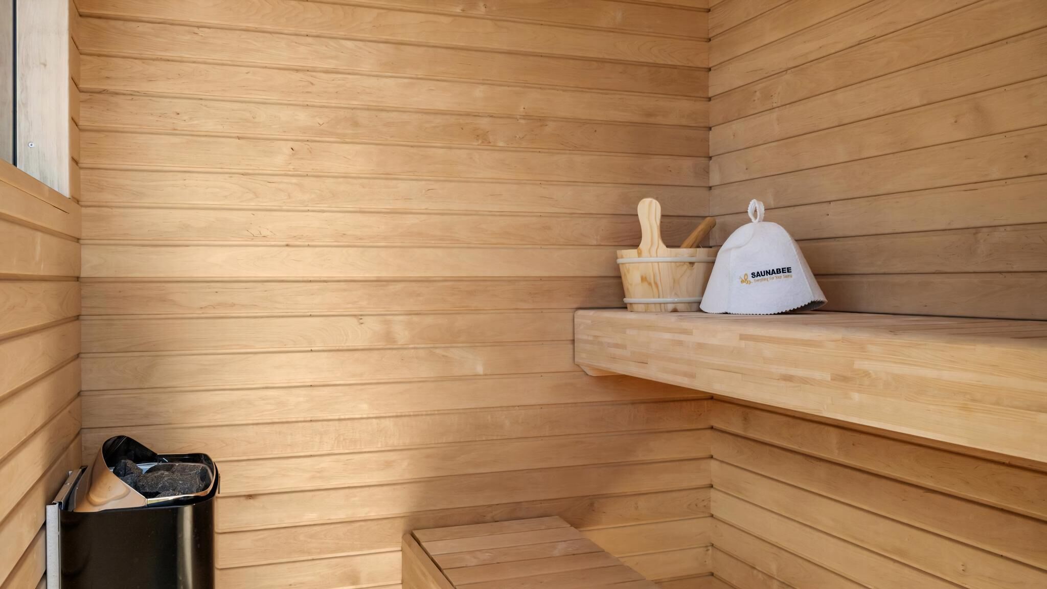 Un sauna avec des murs en bois, un banc, une poubelle et une serviette.