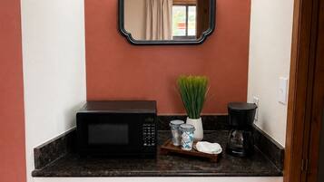 A compact kitchenette with a microwave, coffee maker, and a small potted plant.
