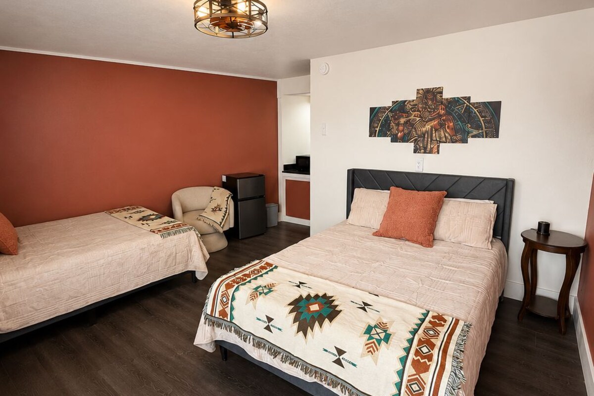 A hotel room with a large bed, a smaller bed, a desk, and a chair.