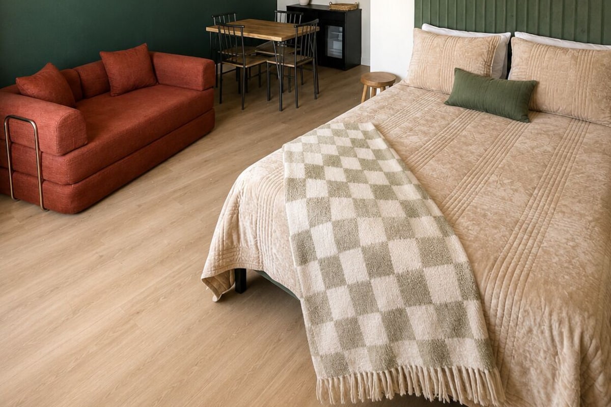 A bedroom with a bed, a sofa, a dining table, and a small desk.