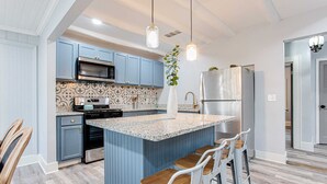 A kitchen with blue cabinets, a central island with bar stools, stainless steel appliances, and hanging pendant lights. - Spacious Bungalow/Close to Airport/Downtown (College Park)