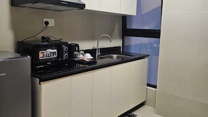 A modern kitchen with white cabinets, a black countertop, a built-in oven, and a window with a view.