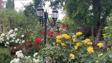 A garden with various flowering plants and two black street lamps.