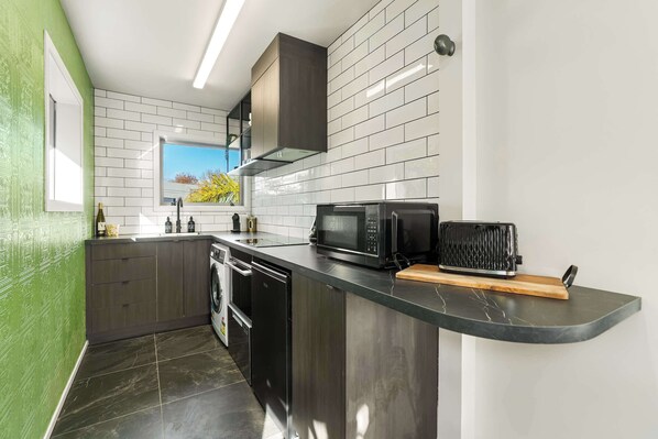 A modern kitchen with a built-in dishwasher, a microwave, and a toaster. - Winifreds Apartments - By Superior Stays (Hamilton)
