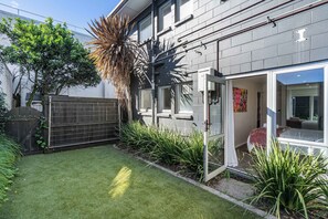 Un bâtiment moderne doté d’une pelouse bien entretenue, d’une clôture en métal et d’une porte donnant sur une pièce offrant une vue agréable.