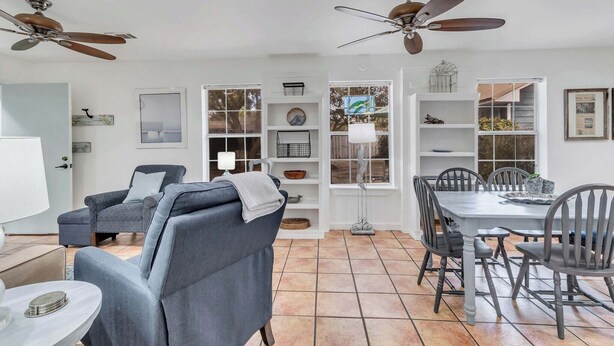 A room with a dining table, chairs, a sofa, ceiling fans, and a window with a view. - Coastal Canopy Cottage, South of 30A, Walk to Beach, Fenced Yard (Santa Rosa Beach)