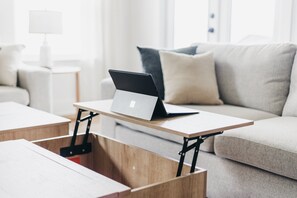 A laptop on a wooden table in a modern living room with a sofa and a lamp in the background. - Grand Gulf Retreat, 5 Bedrooms, Sleeps 13, Garage, Covered Patio (Panama City Beach)
