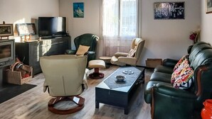 Un salon comprenant un canapé, un fauteuil, une table basse, un téléviseur et des œuvres d’art accrochées aux murs.