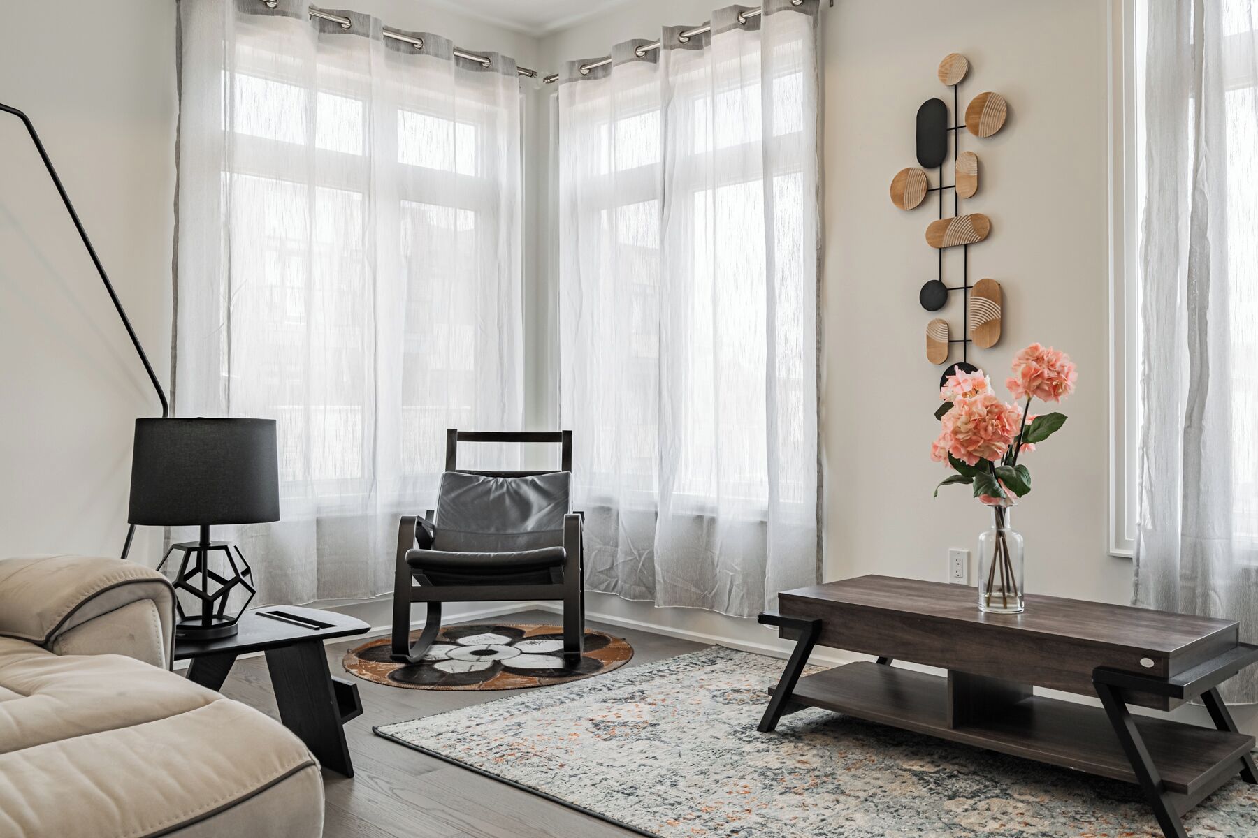 A modern living room with a sofa, a chair, a coffee table, a lamp, and a wall art piece.