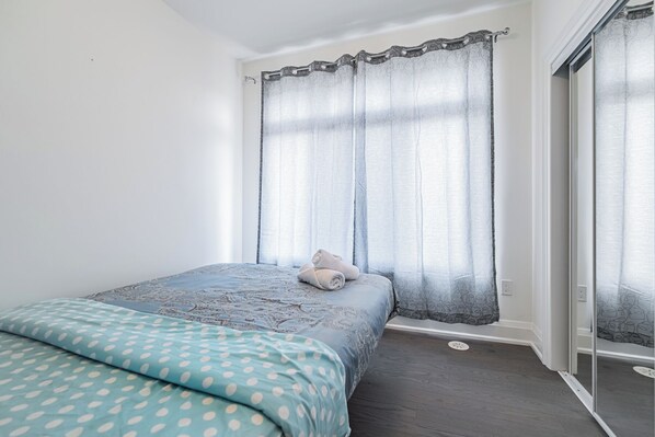 Une chambre à coucher avec un lit, une fenêtre avec un rideau et une porte.