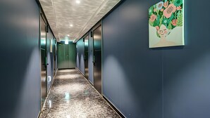 A corridor with a reflective floor, doors on both sides, and a wall-mounted artwork. - Gimpo Airport The Seolleim Hotel Stay Hwagok Station  (Seoul)