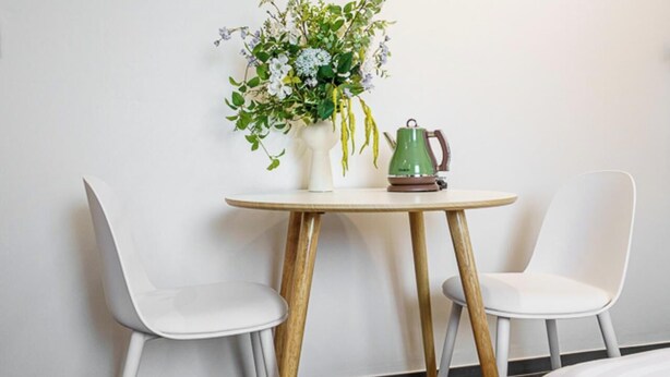A room with a round table, two white chairs, a vase with flowers, and a green kettle. - Gimpo Airport The Seolleim Hotel Stay Hwagok Station  (Seoul)