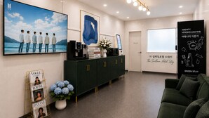 A hotel reception area with a large TV screen, a coffee machine, a vending machine, and a green sofa. - Gimpo Airport The Seolleim Hotel Stay Hwagok Station  (Seoul)