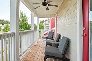A covered porch with two grey lounge chairs, a ceiling fan, and a red door. - Game Room*Hot Tub*Dtown*MTB Trails*Pet Friendly (Bentonville)