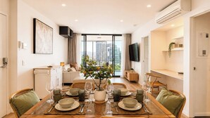 Uma sala de jantar moderna com uma mesa de madeira posta para quatro pessoas, rodeada por cadeiras de vime.