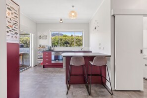 Eine moderne Küche mit einem großen Fenster, einer integrierten Kochinsel mit Barhocker und einem Kühlschrank.