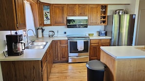 A kitchen with wooden cabinets, a stainless steel refrigerator, a coffee maker, and a microwave.